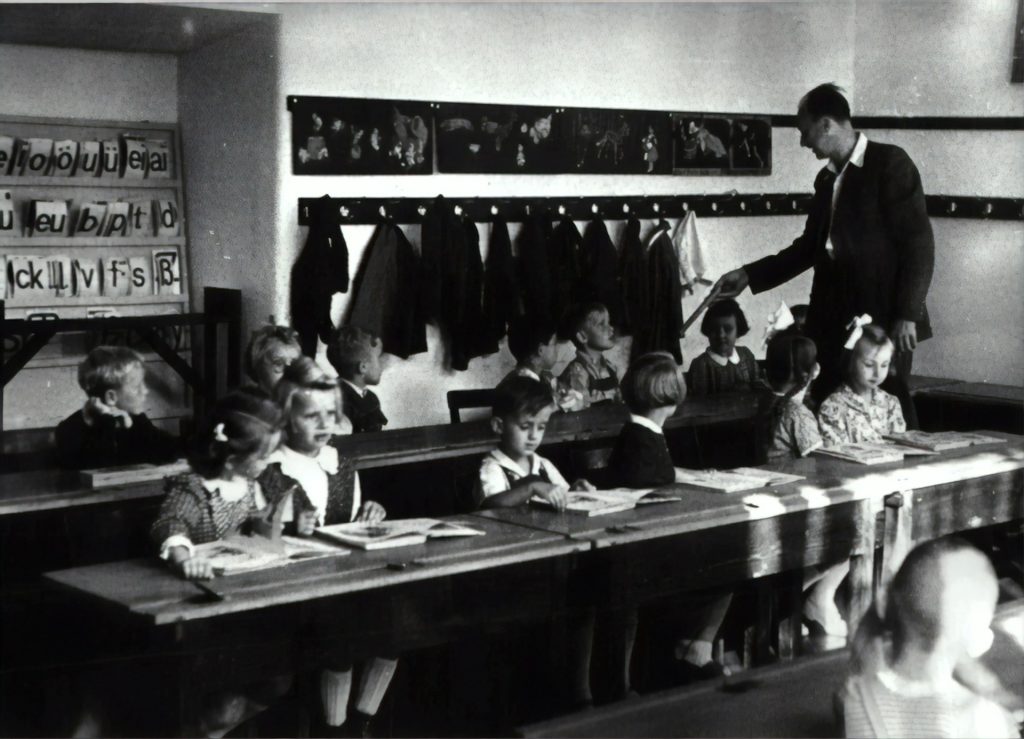1950s classroom with teacher and young learners. 