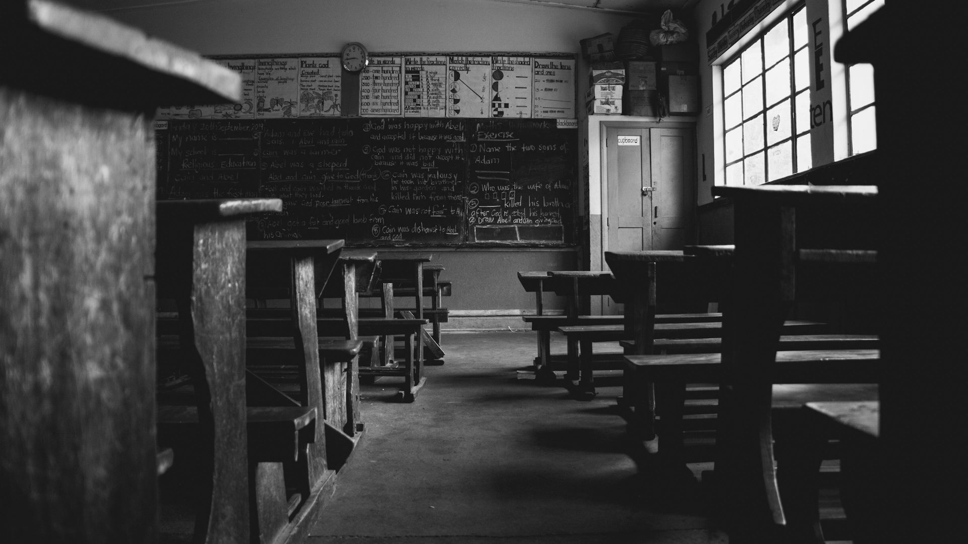 B&W image of classroom with old-fashioned desks.