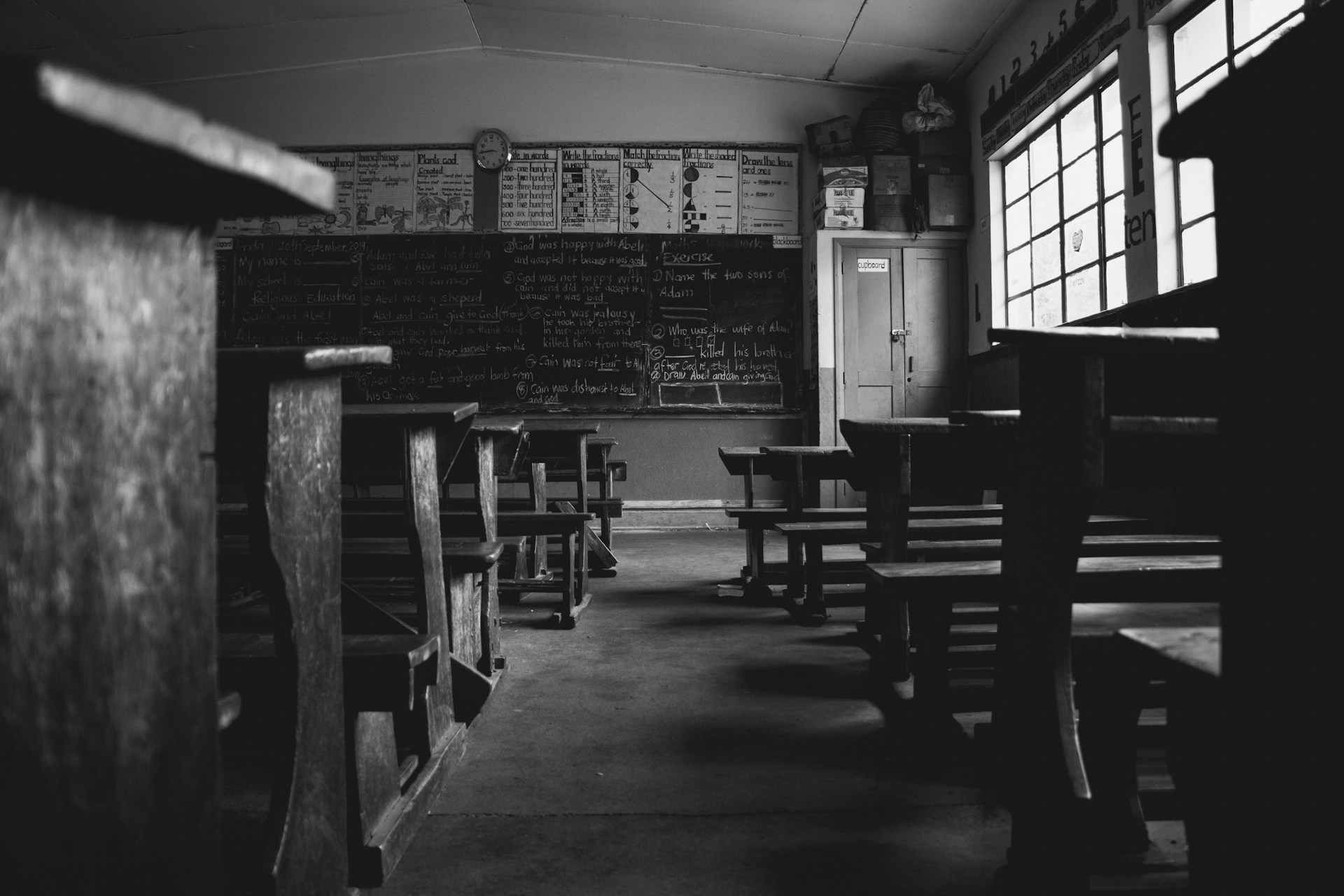 B&W image of classroom with old-fashioned desks.