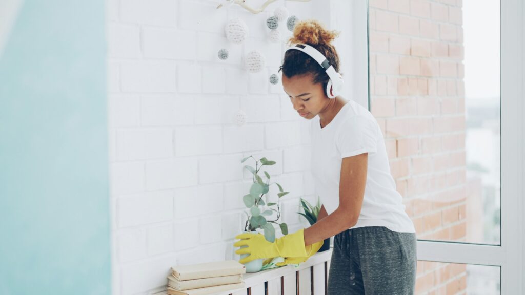 Teenage girl with headphones cleaning counter